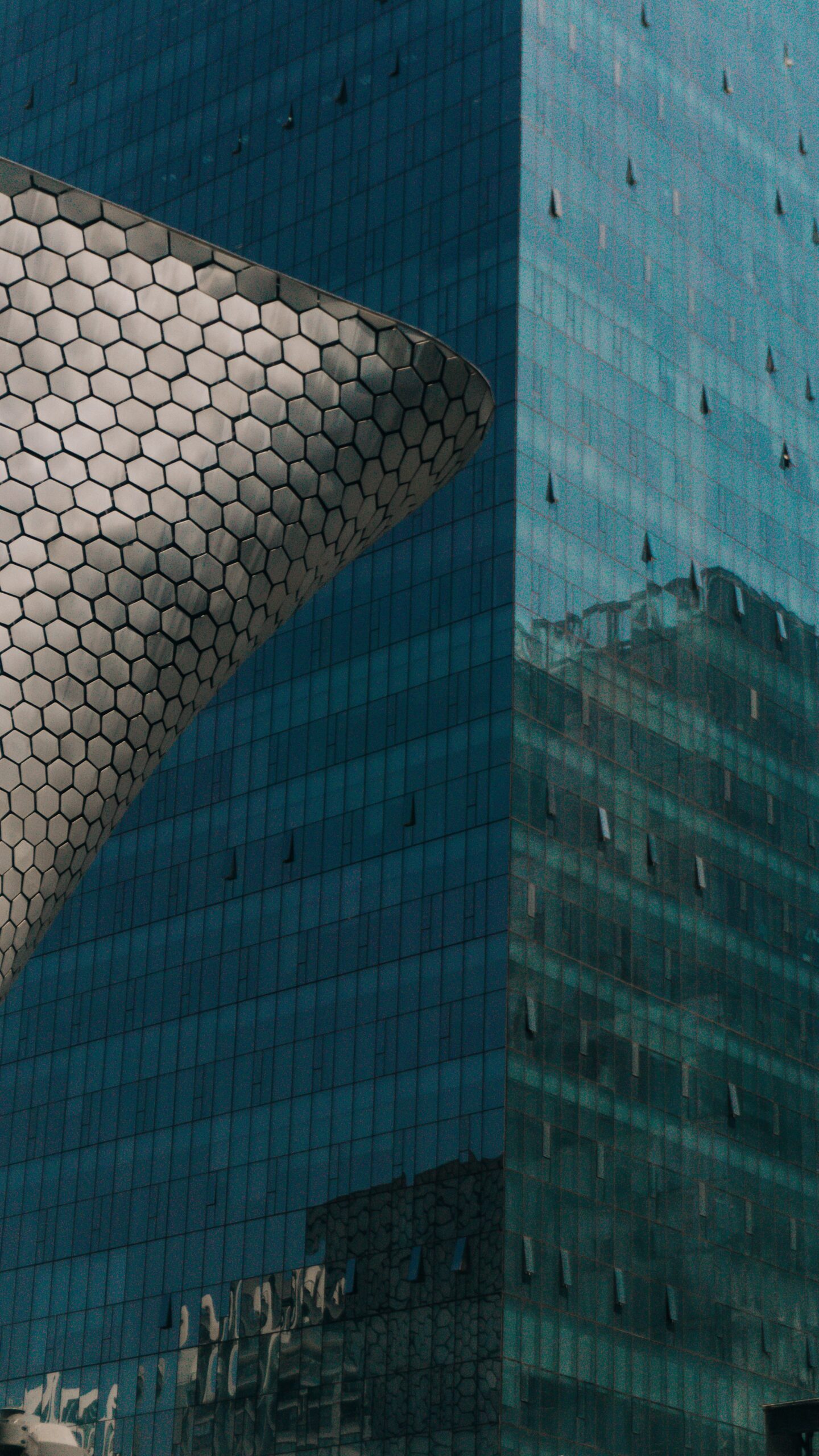 Servicios Reflective glass skyscraper beside modern hexagonal facade in Ciudad de México.